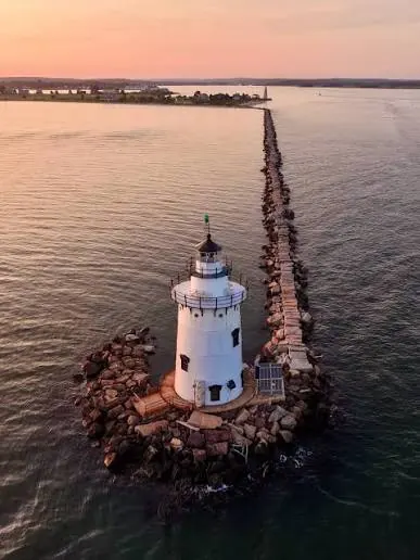 Lighthouse beside a long stone breakwater in Old Saybrook