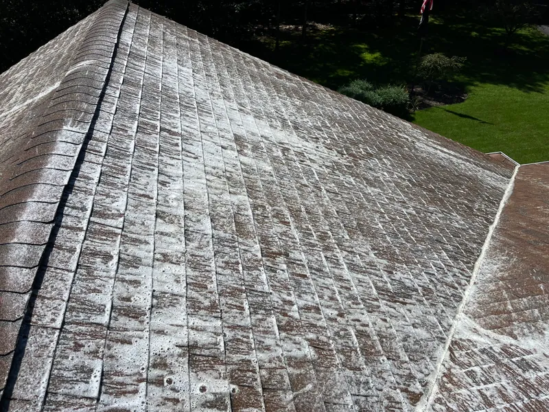 Low-pressure cleaning treatment applied across asphalt roof shingles